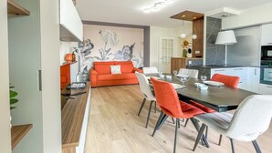 Eine moderne Küche mit Essbereich, ausgestattet mit Holzboden, einer Couch und einem Esstisch mit Stühlen.