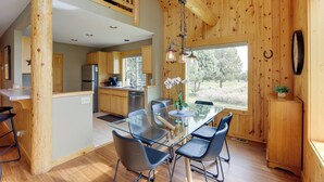 Een moderne keuken met houten details, een glazen eettafel en uitzicht op de omgeving.