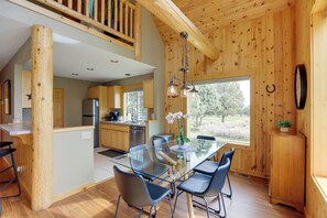 A modern kitchen with wooden accents, a glass dining table, and a view of the outdoors.