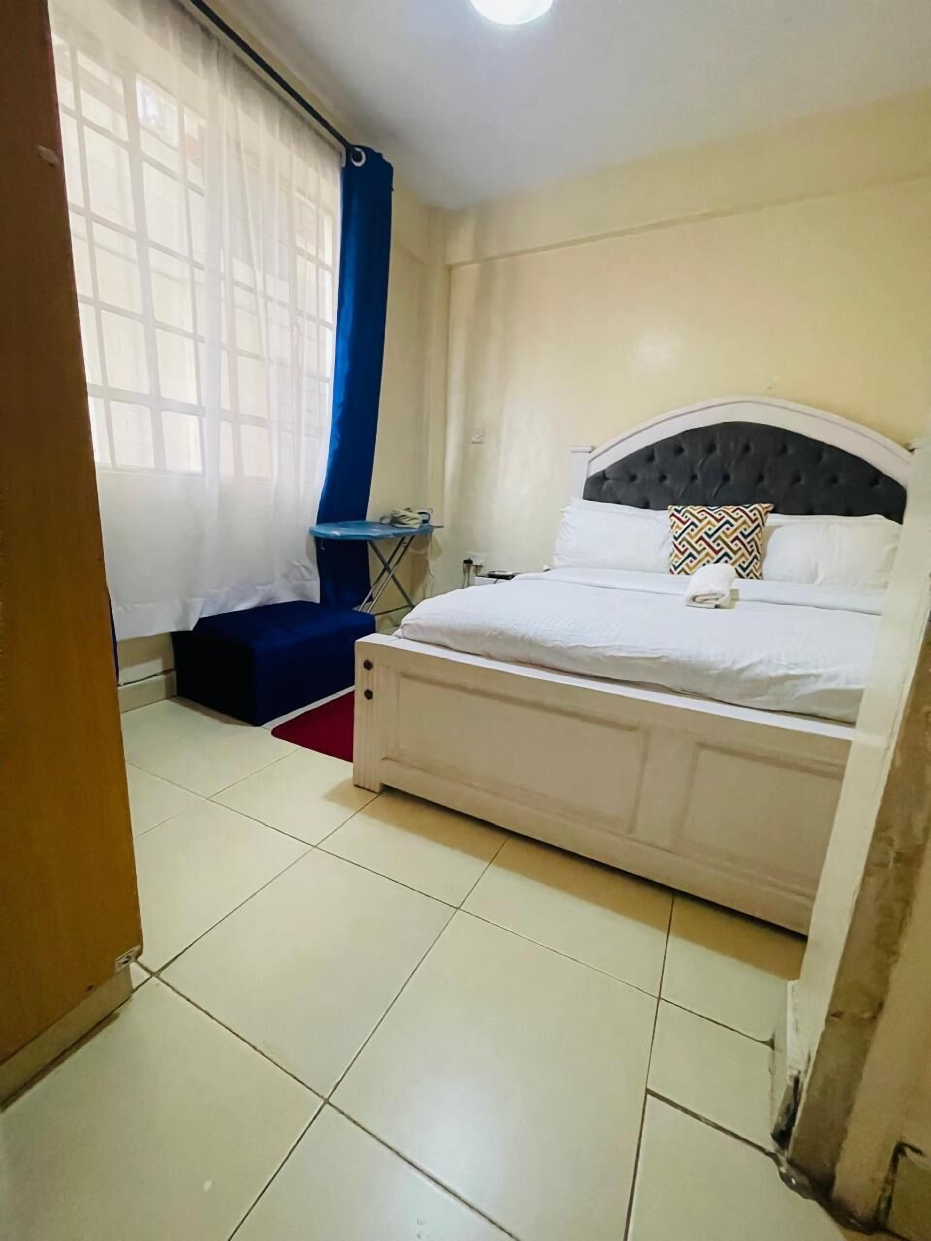 A bedroom with a bed, a small table, and a window with curtains.