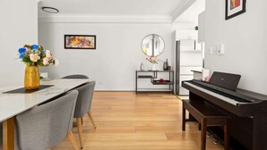 Een moderne woonkamer met een eethoek, een piano en een minimalistische inrichting.