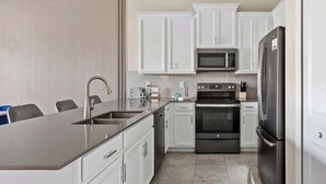 Una cocina moderna con armarios blancos, electrodomésticos de acero inoxidable y una isla grande con fregadero.