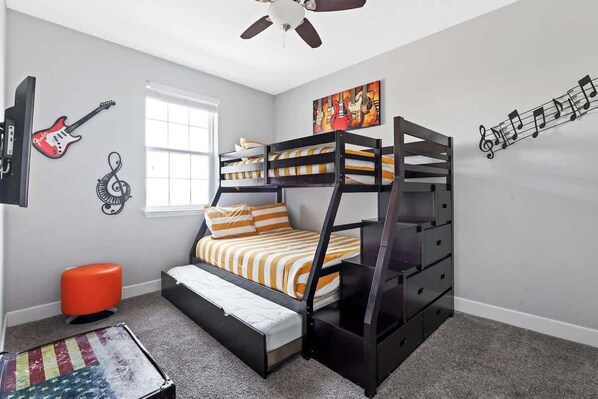 A bunk bed with striped bedding, a ceiling fan, a guitar wall art, and a window.