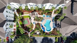 An aerial view of a hotel with a swimming pool, lounge chairs, and palm trees. - Apartment 1 BR FREE Shuttle to Disney Parks (Orlando)