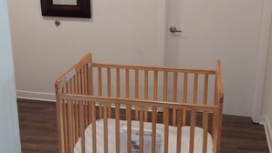 Een kamer met een houten ledikant, een witte deur, een spiegel aan de muur en een ventilatie rooster.