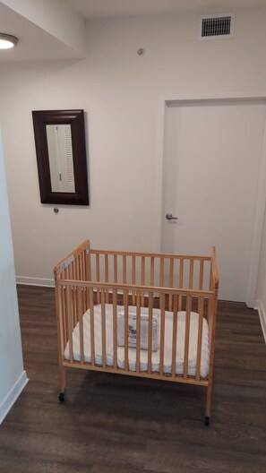 Een kamer met een houten ledikant, een witte deur, een spiegel aan de muur en een ventilatie rooster.