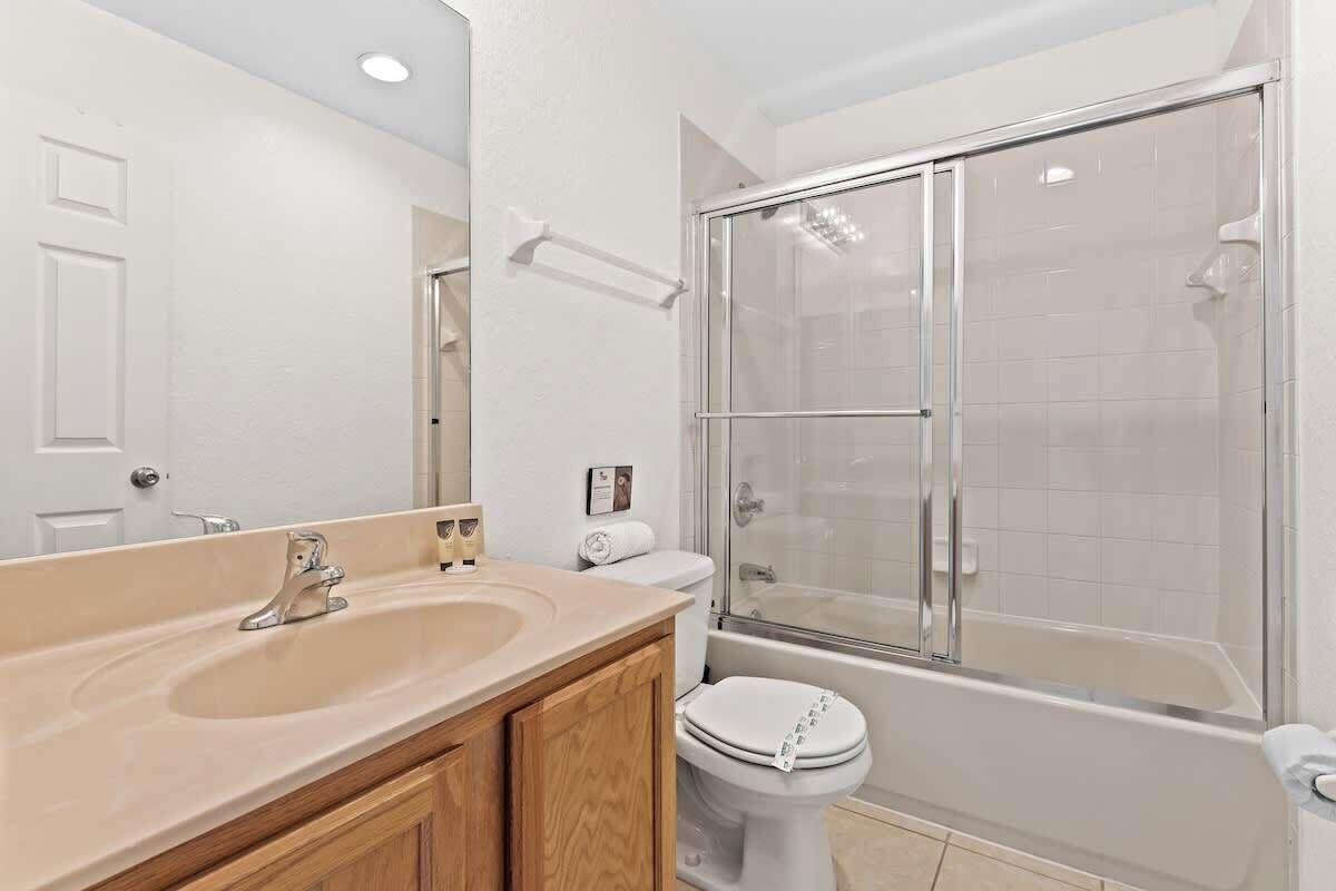 Un baño con lavamanos, inodoro y ducha con mampara de vidrio.