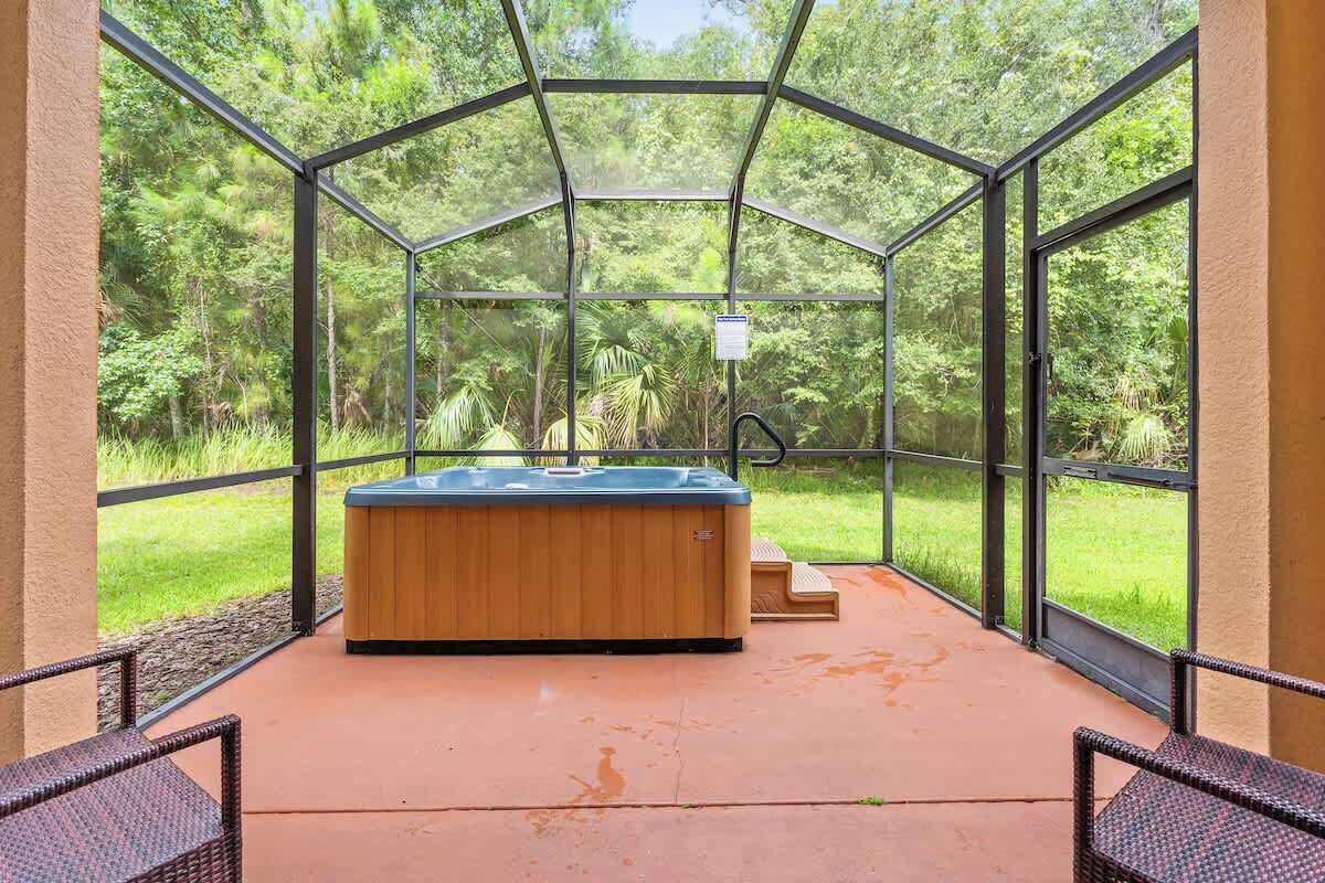Un bain à remous situé dans un espace clos par des parois de verre, offrant une vue sur une forêt luxuriante.