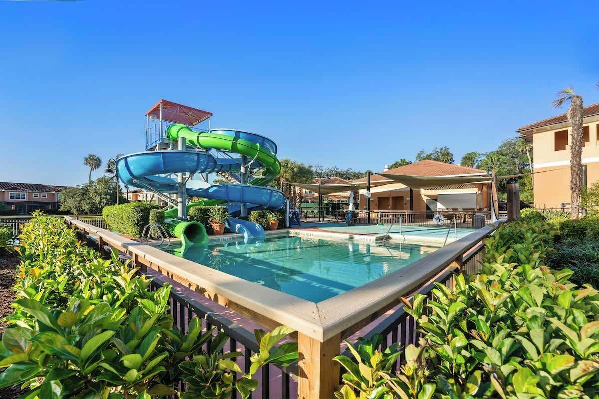 A swimming pool with a water slide and a covered seating area.