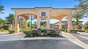A gated entrance with a sign reading "Regal Oaks Welcome" and a logo above it. - Pet Friendly 4 BR with Hot Tub (Kissimmee)