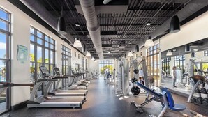Une salle de sport équipée de tapis de course, d’appareils de musculation et de poids libres.
