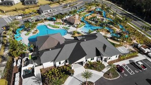 An aerial view of a resort with a swimming pool, parking area, and a building with a sloped roof. - Themed 5 Bedrooms at Storey Lake (Kissimmee)
