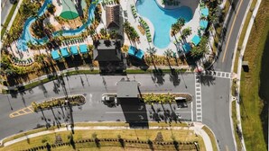 Een vogelperspectief van een resort met een zwembad, terrasgedeeltes en een parkeerplaats.