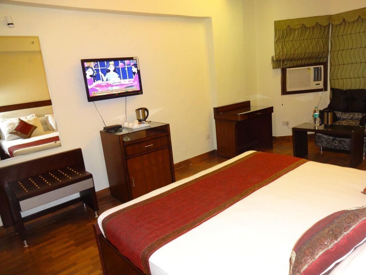 A hotel room with a bed, a television, a desk, and a chair.