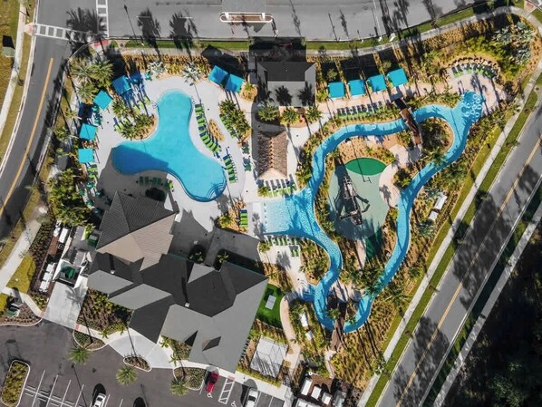 An aerial view of a resort with multiple swimming pools, a large building, and a road nearby.