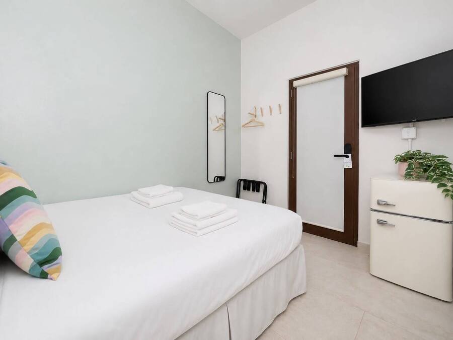 A hotel room with a bed, a dresser, a television, and a door.