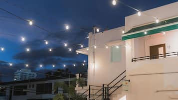 Entrada de un hotel con escaleras, iluminación exterior y un cartel que indica la dirección al vestíbulo.