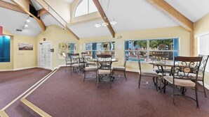 Un vaste espace intérieur doté de hauts plafonds, de poutres en bois et offrant une vue sur la piscine.
