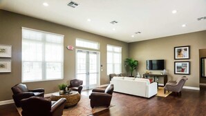 A spacious living room with a dark wood floor, a white sofa, a brown leather chair, and a coffee table.