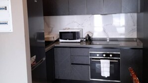 A modern kitchen with dark cabinetry, a microwave, an oven, and a sink.