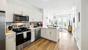 A modern kitchen with stainless steel appliances, white cabinetry, and a wooden floor. - New Modern 1BD/1BA~Pet Love Loft (Austin)