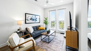 A modern living room with a sofa, armchair, coffee table, and TV stand. - New Modern 1BD/1BA~Pet Love Loft (Austin)