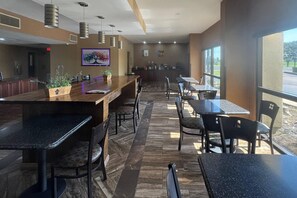 A restaurant with a long counter, multiple tables, and chairs. There are hanging lights, a fire extinguisher, and a window with a view. - Casino Inn and Suites Tunica Resorts (Robinsonville)