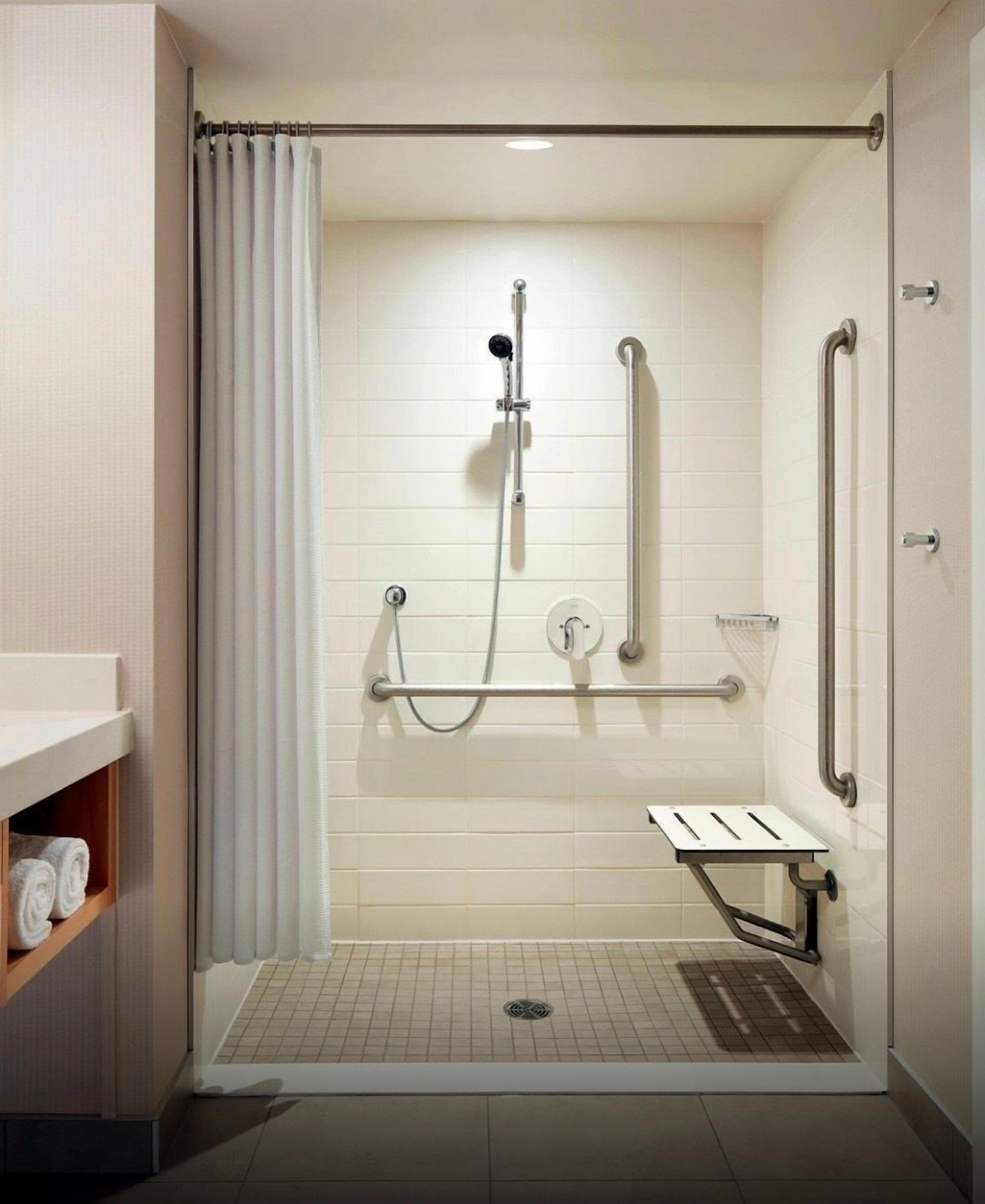 Une douche à l’italienne équipée d’une barre d’appui, d’un porte-serviettes et d’un panneau de commande.