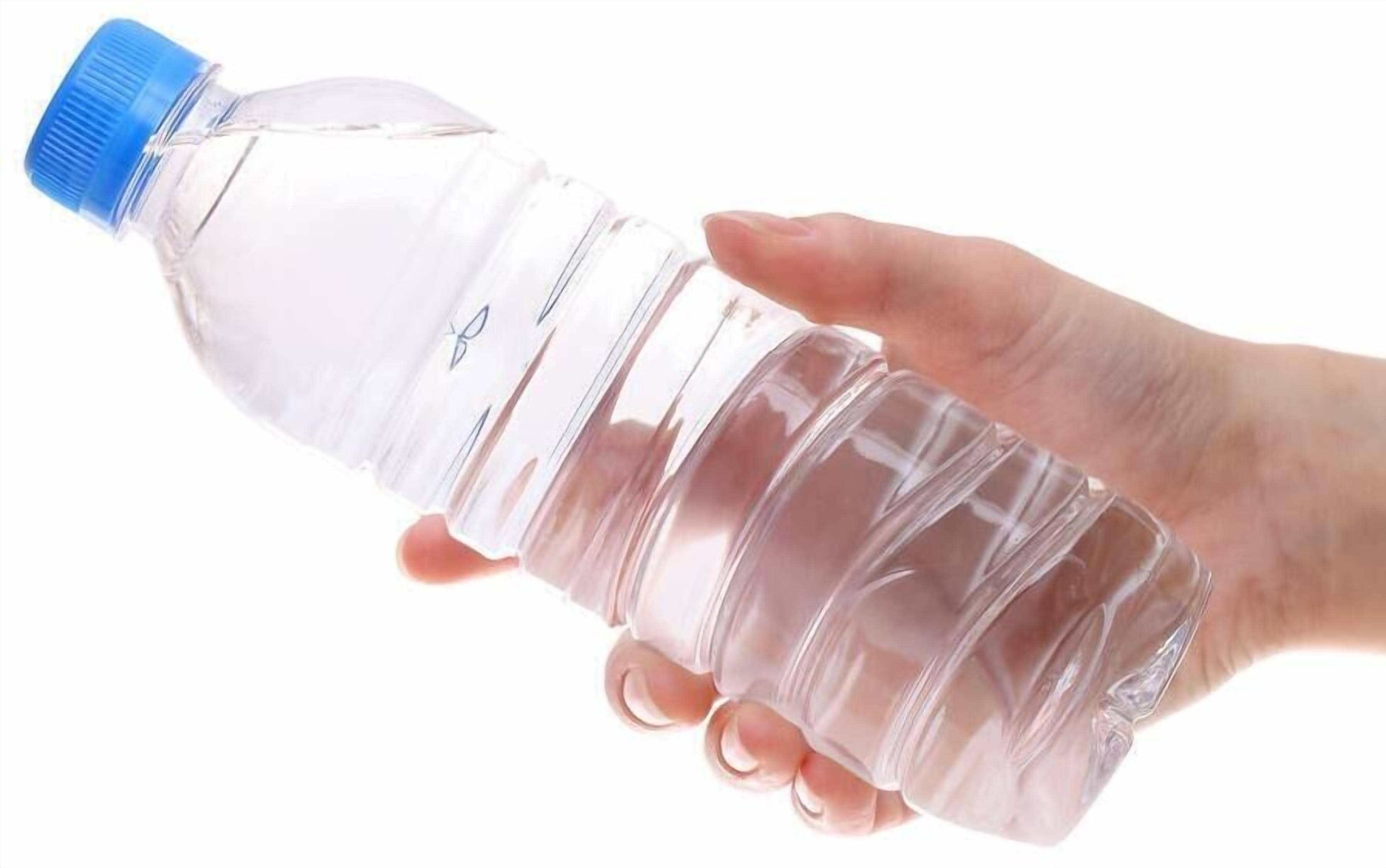 Eine klare Plastikwasserflasche mit blauem Verschluss, gehalten von einer Hand.
