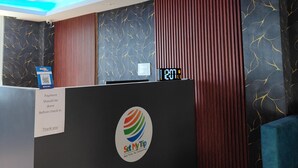 A reception area with a modern design, featuring a black reception desk, a digital clock, and a sign instructing payment before check-in. - The Royal Sheep Residency (Gangtok)