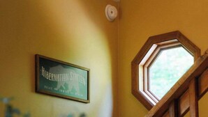 Un escalier en bois avec une rampe en bois, une enseigne encadrée accrochée au mur et une fenêtre donnant sur la verdure.