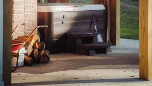 Un bain à remous situé dans un espace extérieur abrité, avec un mur en briques et des poutres en bois.