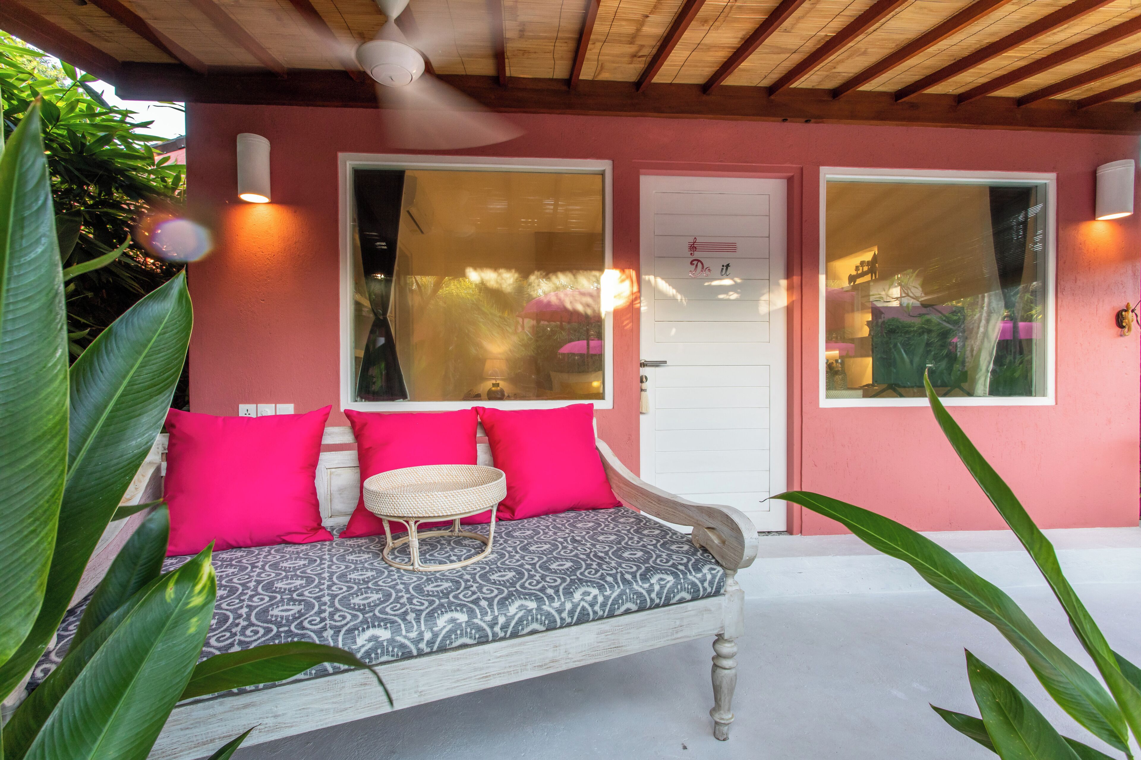 A cozy outdoor seating area with a bench, cushions, and a woven table.
