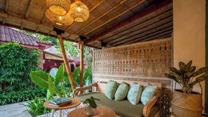 Un espace extérieur accueillant, aménagé avec un banc en bois, une table ronde et un pot de fleurs.