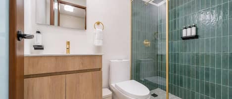 Ein modernes Badezimmer mit einem Holzkosmetikschrank, einer Toilette, einer Duschkabine aus Glas und einem Spiegel.