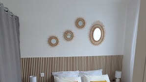 Un dormitorio ordenado con cama, mesitas de noche y decoración en la pared.