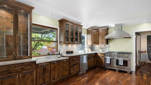 A kitchen with wooden cabinets, a stainless steel stove, and a dishwasher. - Luxury Retreat • Pool, Hot Tub • Cigar Lounge (Santa Rosa)