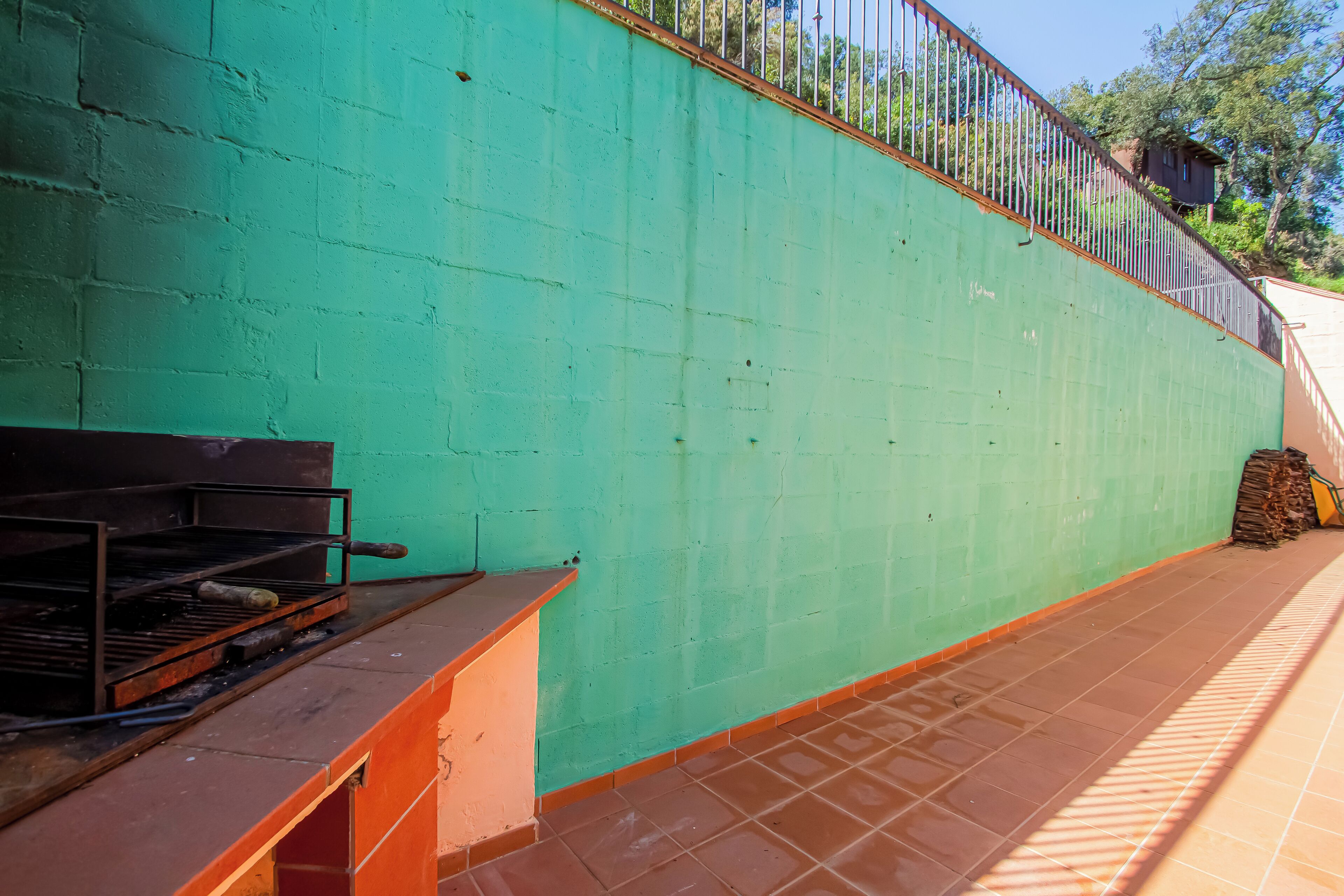 A brick wall with a metal railing and a grill.