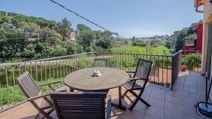 A balcony with a round table and chairs, overlooking a river and greenery. - Club Villamar - Charming house with pool in the Rio de Oro urbanisation – Calonge (Calonge)