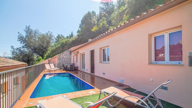 A swimming pool with lounge chairs and a stone wall. - Club Villamar - Charming house with pool in the Rio de Oro urbanisation – Calonge (Calonge)