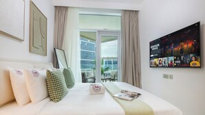 Een hotelkamer met een groot bed, een televisie aan de muur en een balkon met uitzicht over de stad.