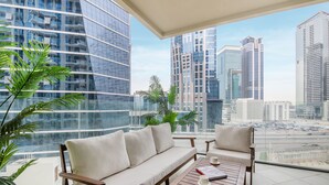 Een balkon met een bank en stoelen, met uitzicht op een stadsgezicht met moderne wolkenkrabbers.