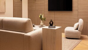 A modern living room with a sofa, a coffee table, and a TV mounted on the wall. - Sublime Air-conditioned Flat Le Marais (Paris)
