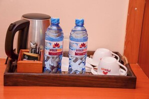 A tray with a kettle, two water bottles, a small box, and a set of white cups and saucers. - Breeze Hotel Nyahururu (Nyahururu)