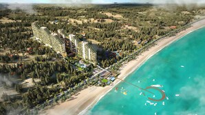An aerial view of a coastal resort with multiple high-rise buildings, a beachfront, and a marina with boats. - Apec Mandala Mũi Né Resorts & Hotels NN (Mui Ne)