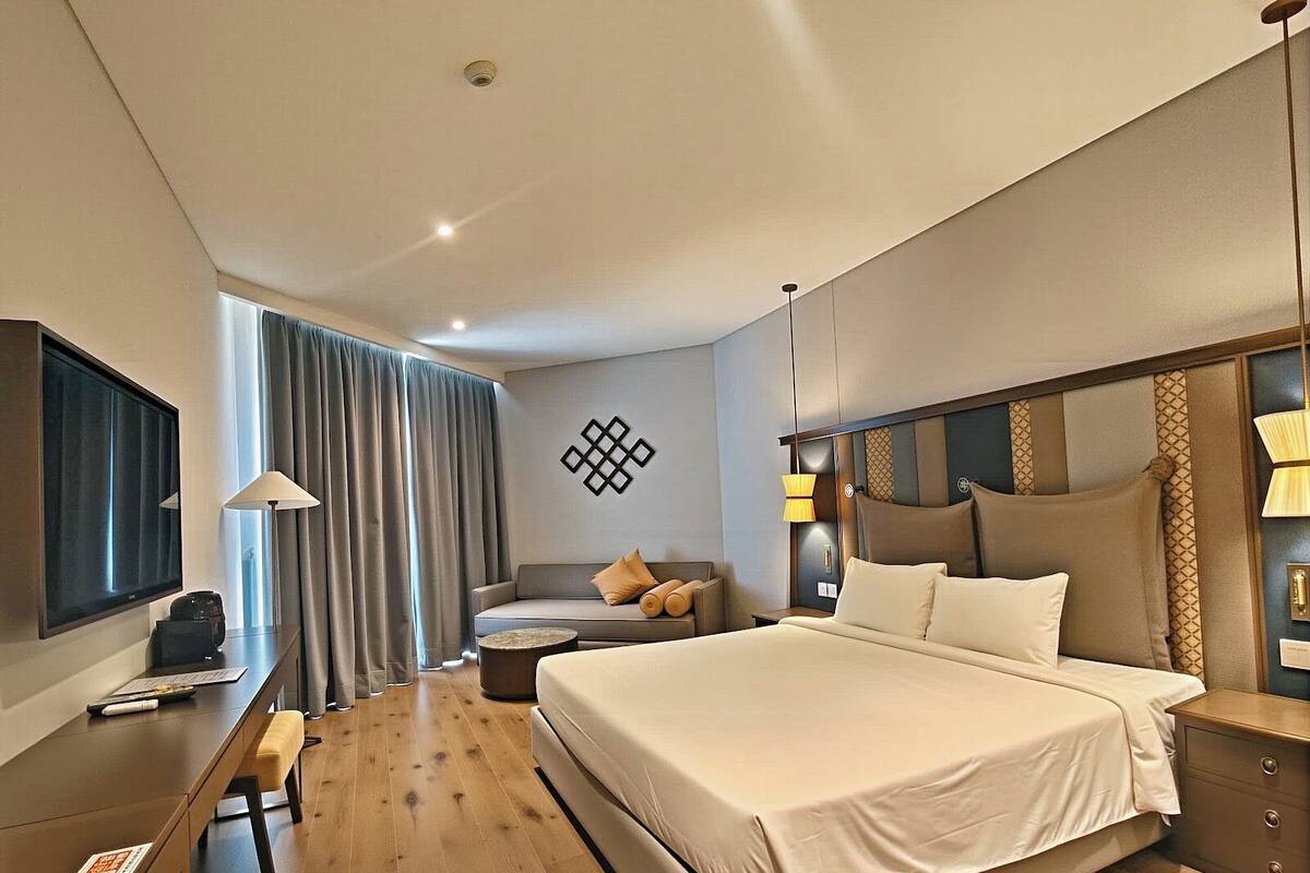Une chambre d’hôtel moderne dotée d’un grand lit, d’un bureau, d’une chaise, d’une télévision et offrant une vue sur l’extérieur.