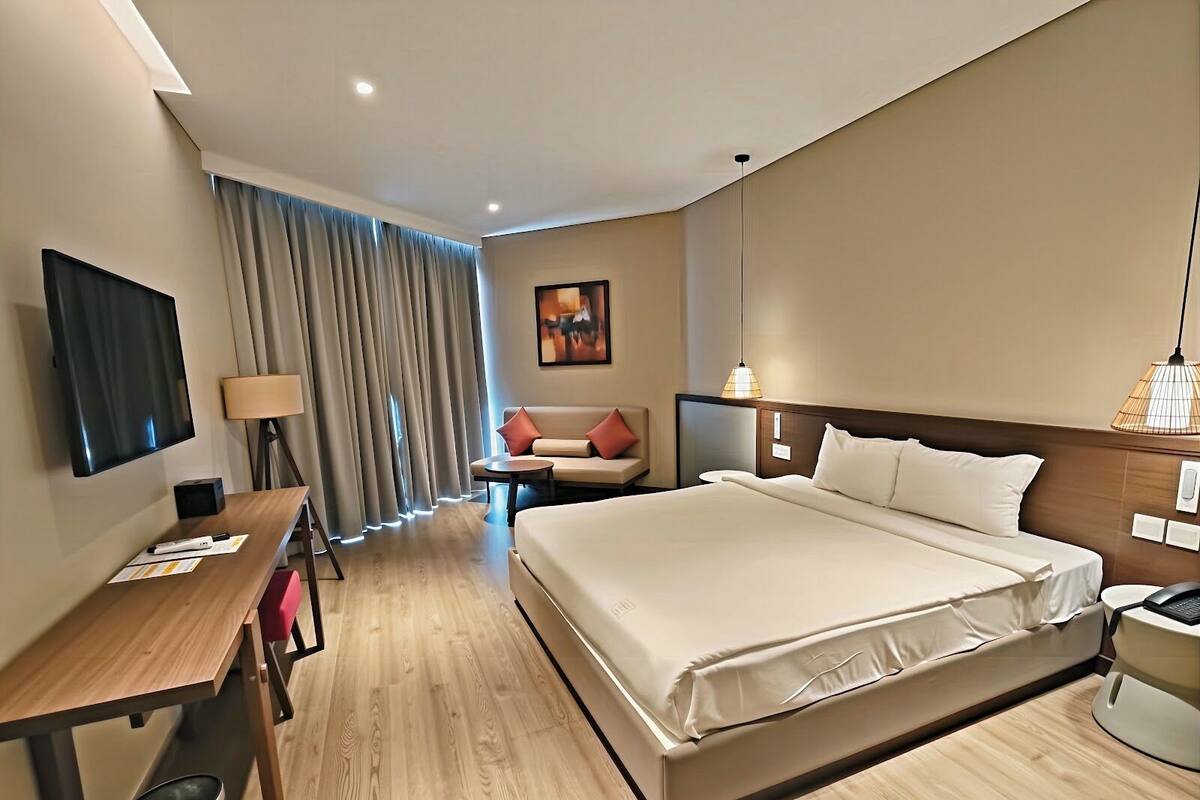 Une chambre d’hôtel moderne équipée d’un grand lit, d’un bureau, d’une chaise et d’une télévision.