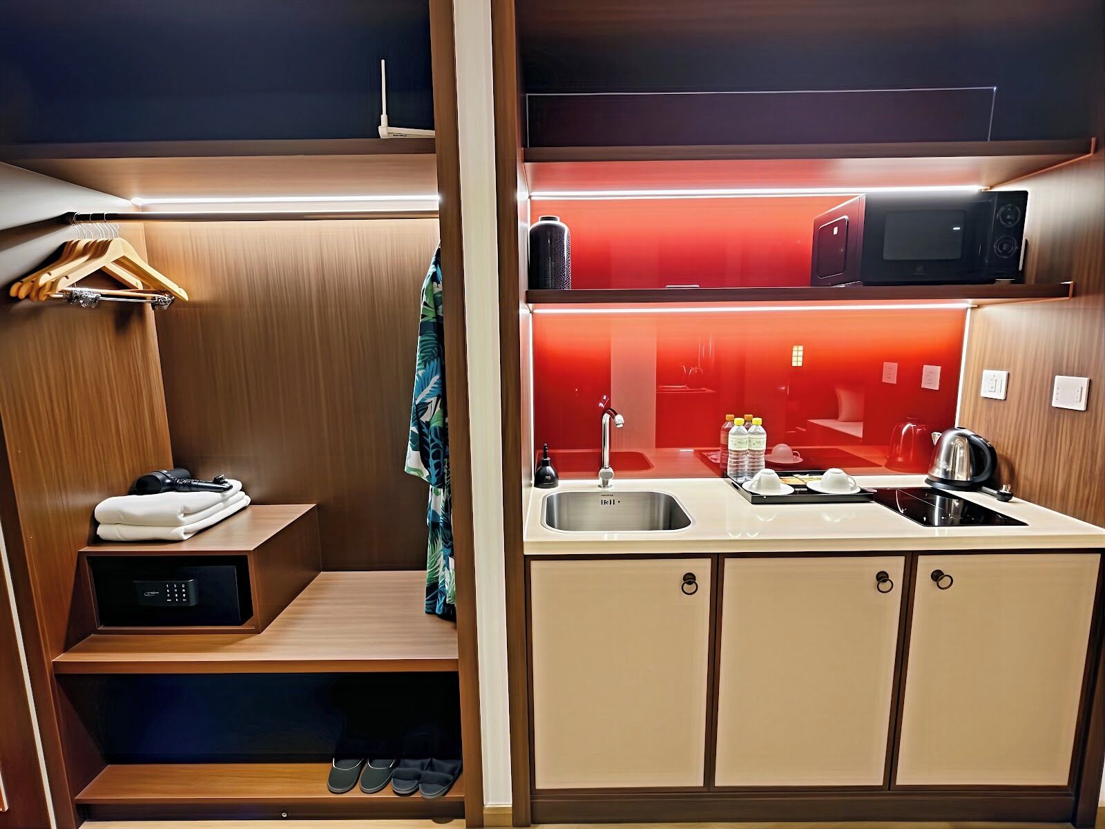 A compact kitchenette with a microwave, kettle, and sink.