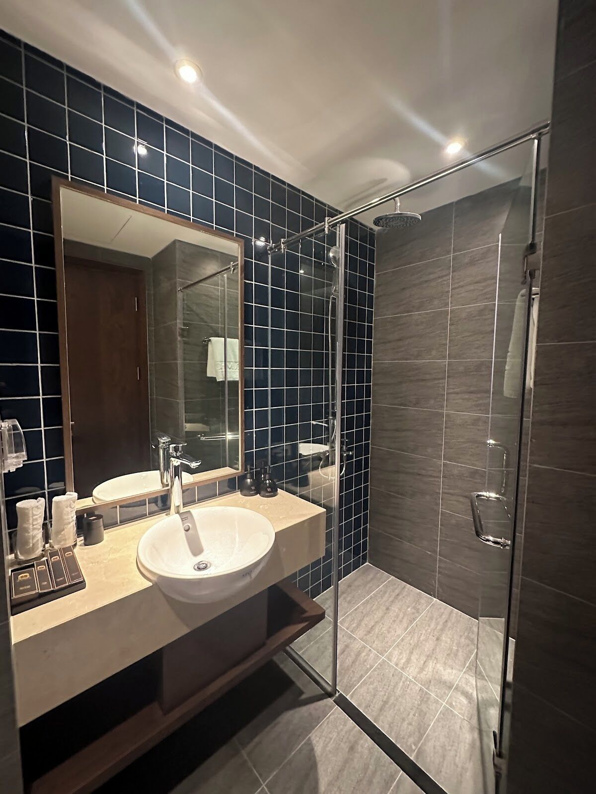 Un baño moderno con un espejo grande, un lavabo y una ducha con mampara de vidrio.