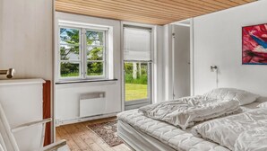 Un dormitorio con cama, ventana, radiador y un cuadro.